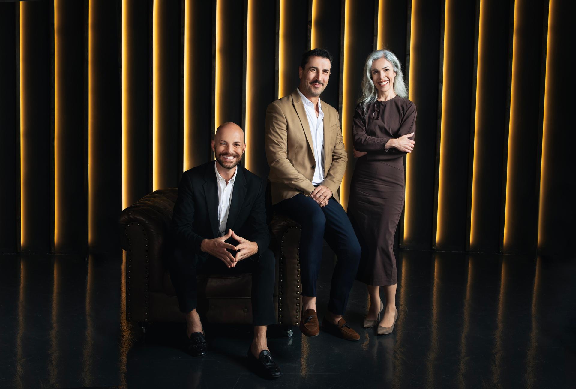 Three Smiling Business Professionals Posing In Dark Office Luxury Interior